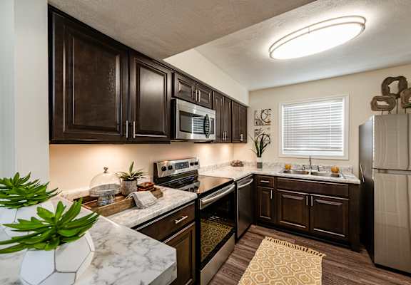 A kitchen with dark brown cabinets and a white countertop.