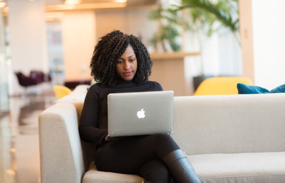 a woman sitting on a couch using a laptop computer