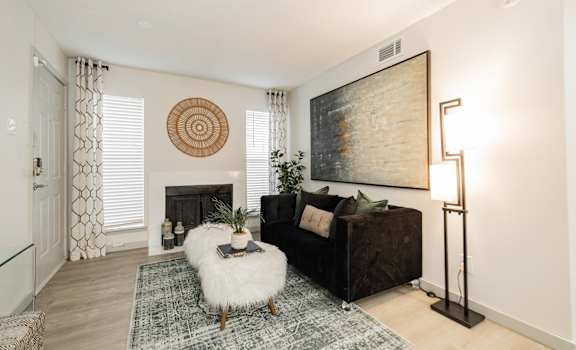 A living room with a fireplace, a couch, a rug, and a painting on the wall.
