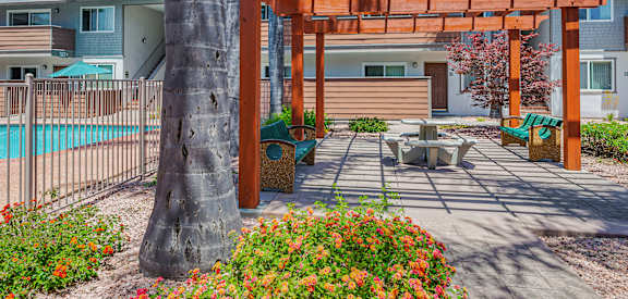 A wooden pergola is over a patio with a table and chairs.