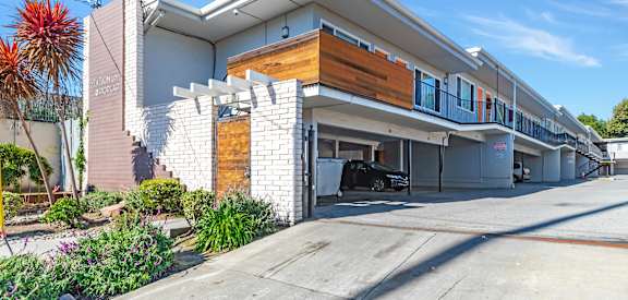 A modern two-story building with a garage and a car parked in it.