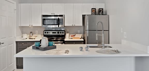 A kitchen with a white counter top and a stainless steel refrigerator.