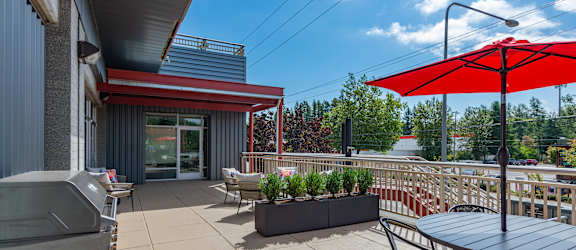 A patio with a table, chairs, and a red umbrella.
