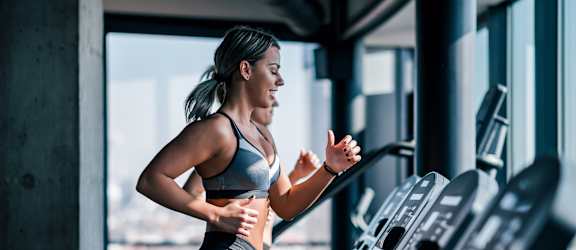 A woman is running on a treadmill in a gym.