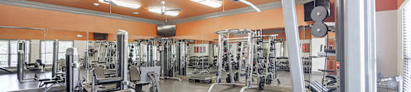 A gym with a variety of equipment including a leg press machine at Cumberland Place Apartment Homes, Tyler 75703