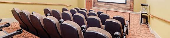A movie theater with rows of seats and a large screen at the front at Cumberland Place Apartment Homes, Tyler, TX