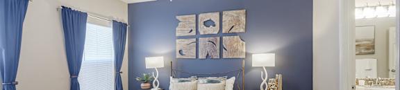 A bedroom with a bed, nightstands, and a ceiling fan at Cumberland Place Apartment Homes, Texas 75703