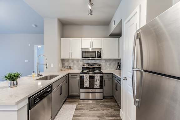 A modern kitchen with stainless steel appliances and a marble countertop.