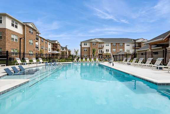 A large swimming pool in front of apartment buildings.