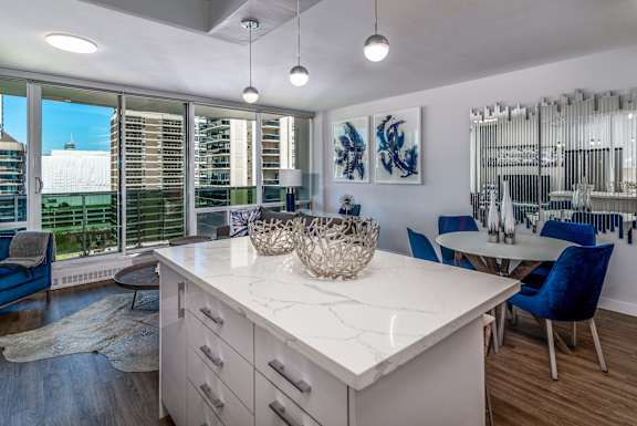 A kitchen with a white countertop and blue chairs.