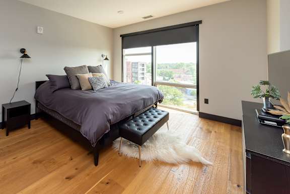 A bedroom with a bed, a bench, and a window.