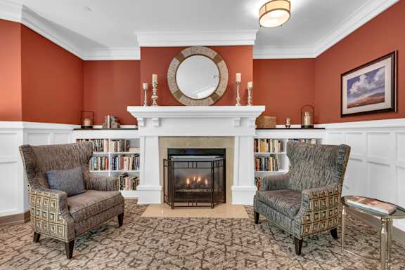 A living room with a fireplace and two chairs.