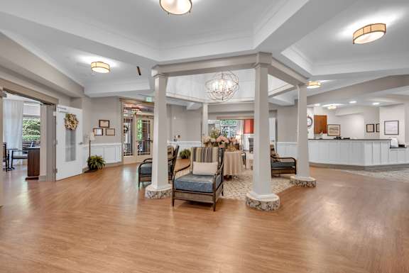 A spacious lobby with a wooden floor and a large chandelier.