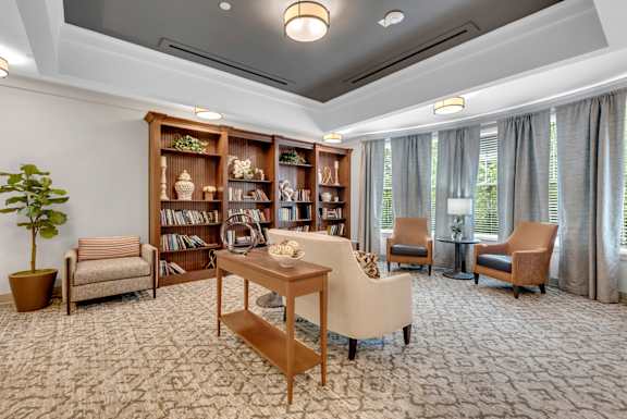 A living room with a carpeted floor and a bookshelf filled with books.