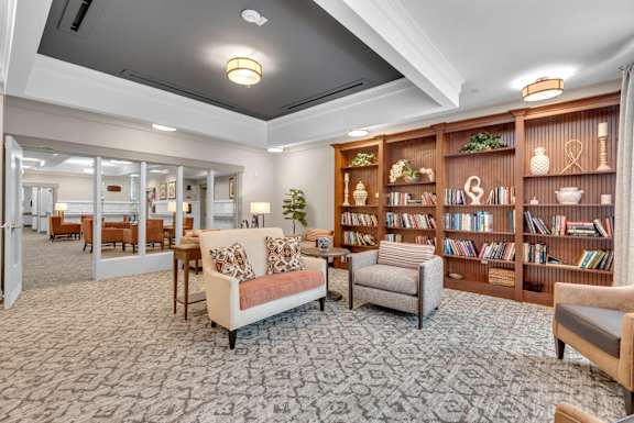 A living room with a couch, chairs, and a bookshelf.