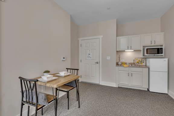 A kitchen area with a table and chairs.