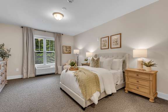 A bedroom with a large bed, a window with curtains, and a nightstand with a plant on it.