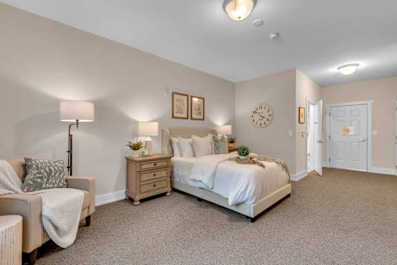 A bedroom with a bed, nightstand, and chair.