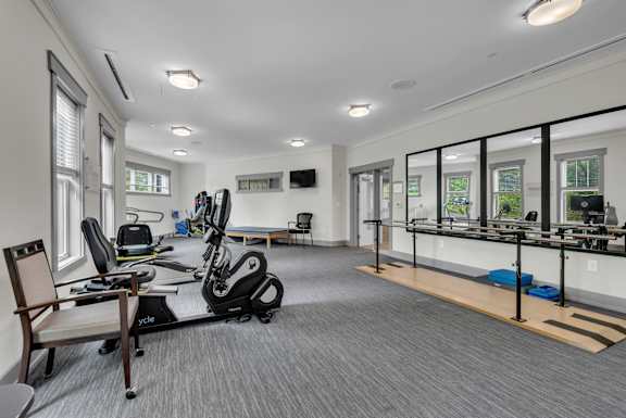 A spacious gym with a variety of equipment including a treadmill, exercise bike, and a bench.