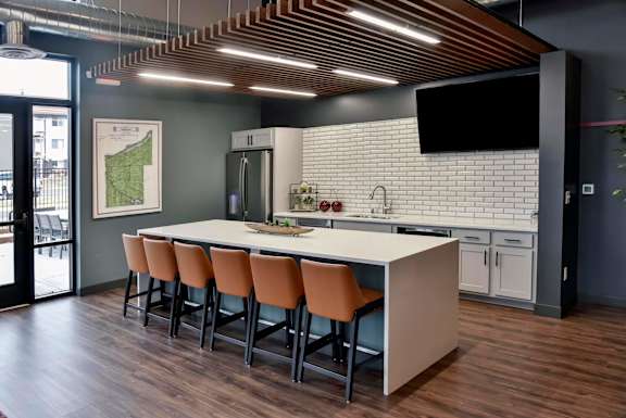 a kitchen with a large island with a white counter top and orange chairs