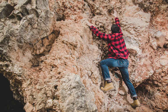 A man climbs a rock at Red Rock Apartments, Rapid City