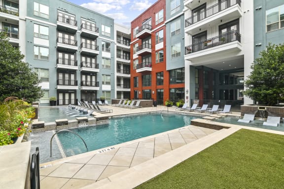 an apartment building with a pool and fountain in front of it