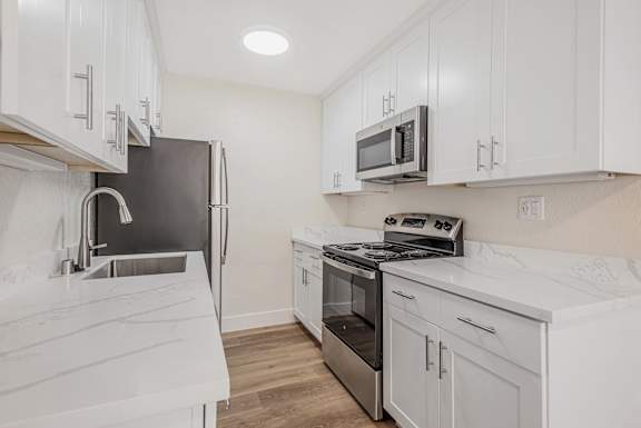 a kitchen with white cabinets and a stove and sink