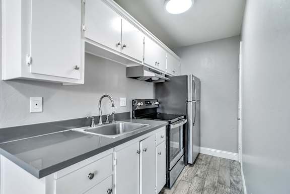 A kitchen with white cabinets and a stainless steel sink.