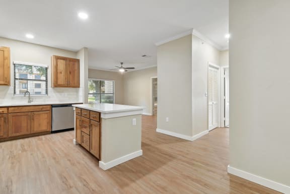 an open kitchen and living room with white walls and wood flooring at The Canyons Apartments, Fort Worth, TX