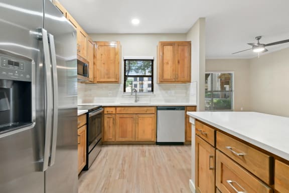 a kitchen with stainless steel appliances and wooden cabinets at The Canyons Apartments, Fort Worth, TX