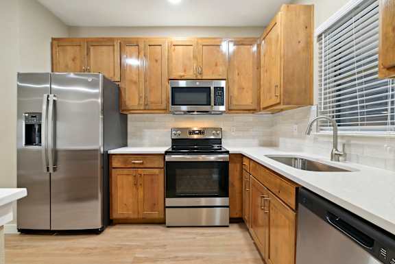 a kitchen with stainless steel appliances and wooden cabinets at The Canyons Apartments, Fort Worth, 76116