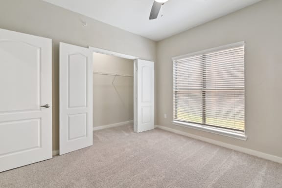 an empty bedroom with a large window and closet at The Canyons Apartments, Fort Worth, TX