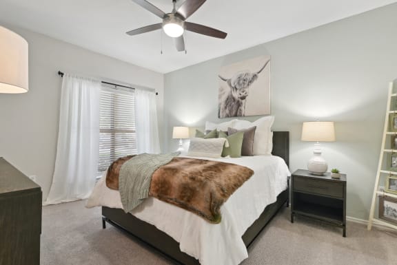 an empty bedroom with a bed and a ceiling fan at The Canyons Apartments, Texas