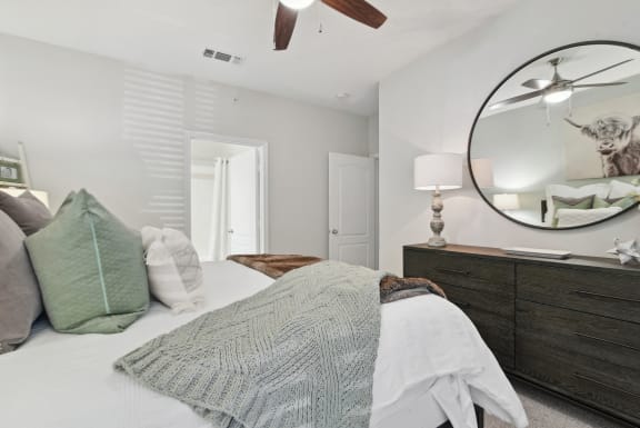 a bedroom with a bed and a mirror on the wall at The Canyons Apartments, Texas