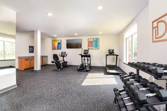 A gym with a variety of equipment including weights and a treadmill.