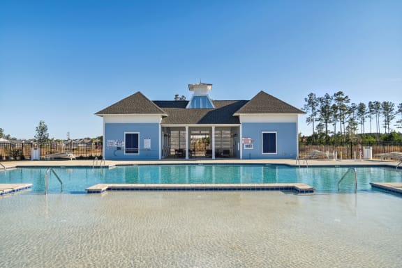 a large swimming pool in front of a house with a blue building