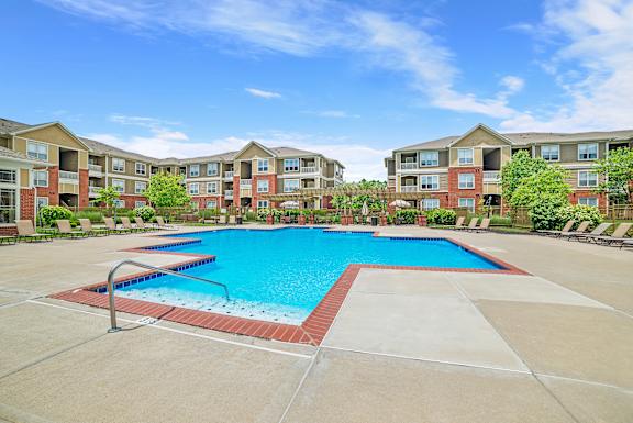 A large swimming pool surrounded by lounge chairs and umbrellas.