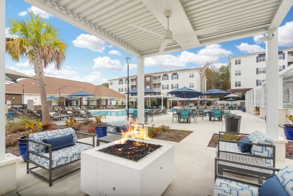 a swimming pool with chaise lounge chairs and a pool house in the background at The Met Apartment Homes in Mississippi 39402