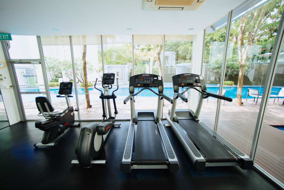 a room with a treadmill and a pool in the background