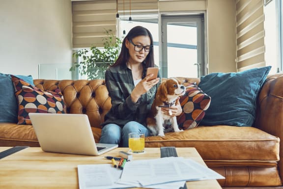 a woman sitting on a couch holding a dog and looking at her cell phoneat First Street Lofts in Downtown Bismarck, Bismarck, ND, 58506