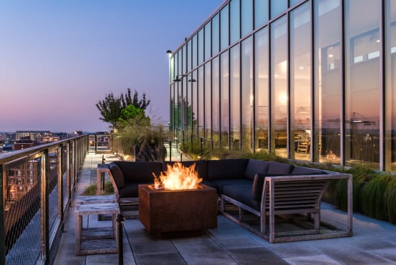 a lounge area with a fire pit and chairs on a balcony