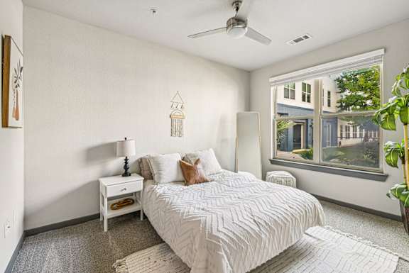 A bedroom with a large bed and a window overlooking a building.