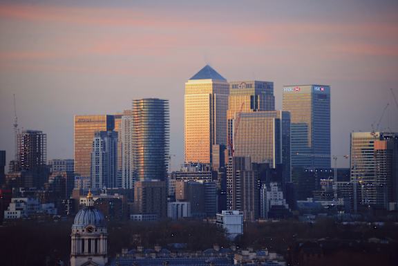 A city skyline at sunset with a mix of modern and older buildings.