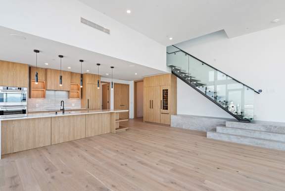 A modern kitchen with wooden floors and a glass staircase. at Olympic + Hill Apartments, Apartments, Los Angeles, CA