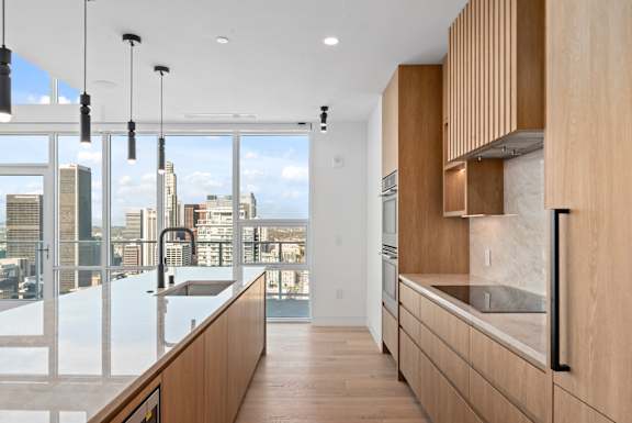 A modern kitchen with wooden cabinets and a view of the city. at Olympic + Hill Apartments, Apartments, Los Angeles, CA