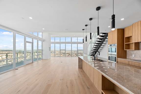 A modern kitchen with wooden floors and a staircase leading to the upper level. at Olympic + Hill Apartments, Apartments, Los Angeles, CA