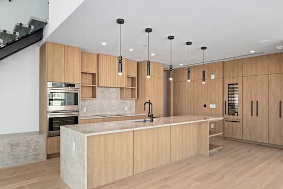 A modern kitchen with wooden cabinets and a marble island. at Olympic + Hill Apartments, Apartments, Los Angeles, CA