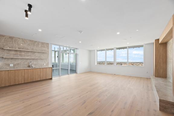 A spacious room with wooden floors and a large window overlooking the desert. at Olympic + Hill Apartments, Apartments, Los Angeles, CA