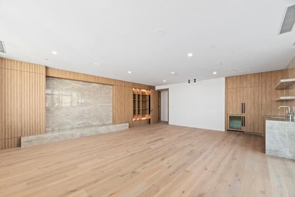 A room with wooden floors and a white wall with a small TV on it. at Olympic + Hill Apartments, Apartments, Los Angeles, CA