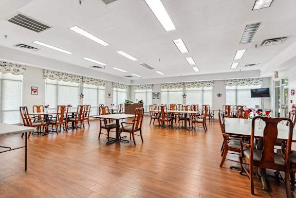 A large room with wooden floors and tables and chairs.